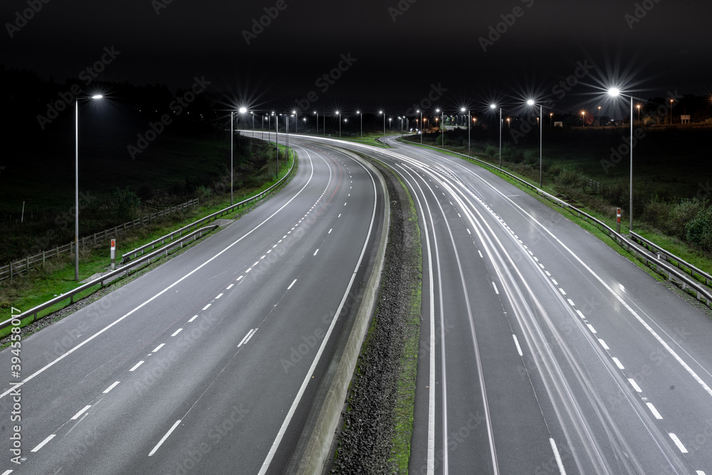 Autostrada nocą z latarniami i samochodami