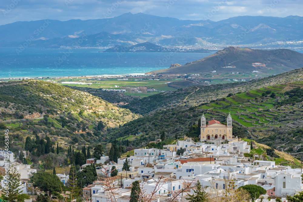 panorama view of traditional architecture with whitewashed houses and the cristian church of Agia Triada in the traditional village  lefkes in Paros island, Greece and naxos island as background