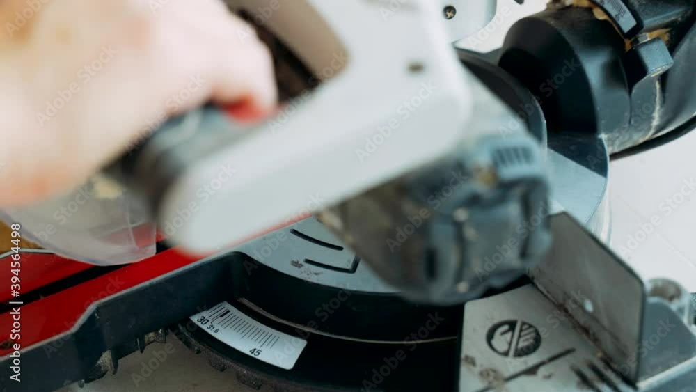 A worker cuts off a laminated board with an electric miter saw. Laying the floor covering. A worker cuts off a laminated board with an electric miter saw. Laying the floor covering.