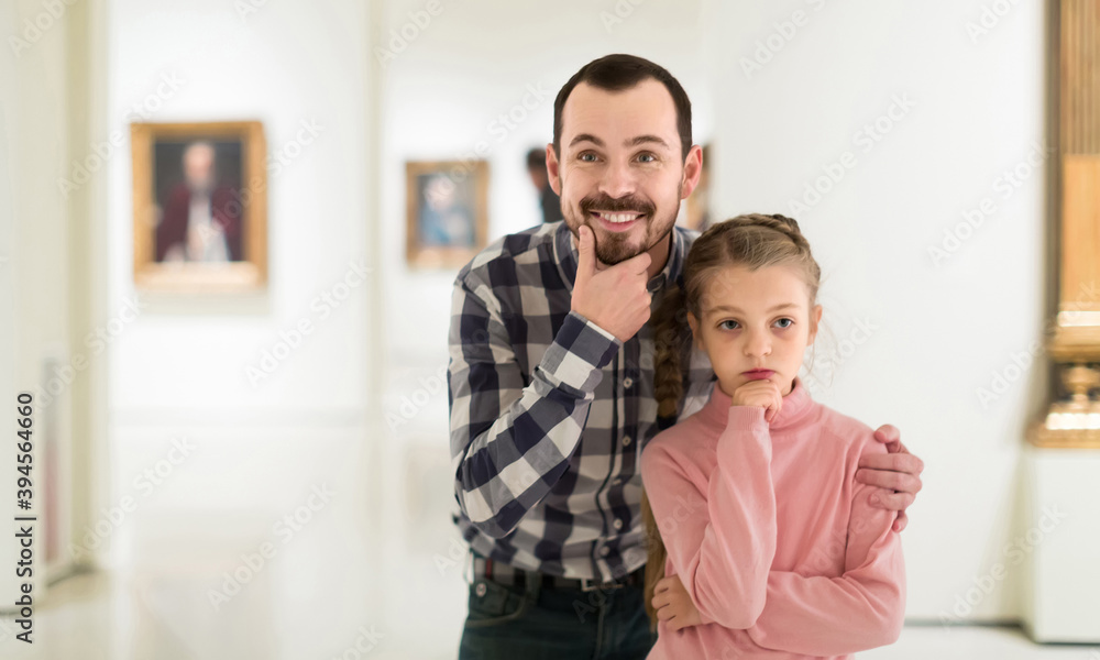 young european father and daughter looking at paintings in halls of museum