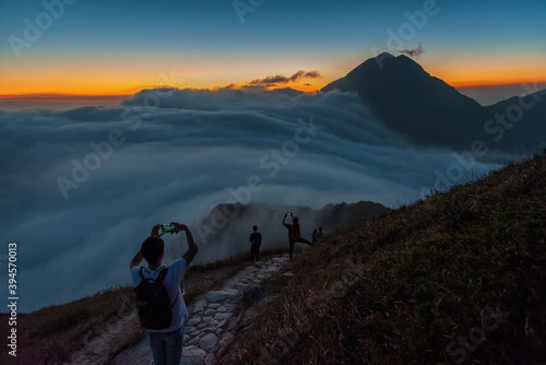 Hiker taking photo of Mountain Fung Wong Shan - Lantau Peak from Sunset Peak at dusk. Natural landmark in hong kong