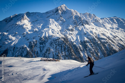 Skier going down the slope. Mountains covered with snow in Solden ski area on beautiful sunny winter day, Tirol, Austria photo