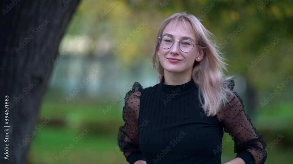 Portrait of an attractive blonde girl with glasses walking along a city street on an autumn day, smiling and posing. Portrait of an attractive blonde girl with glasses walking along a city street on an autumn day, smiling and posing.