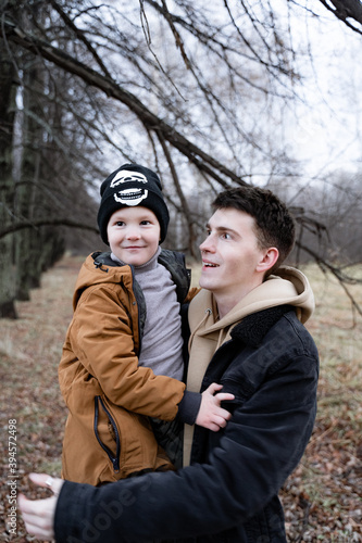 a close-up portrait of a father and son, a boy is laughing in his dad's arms, a father with a nose piercing is raising a child, modern society, a son is growing up in an informal family