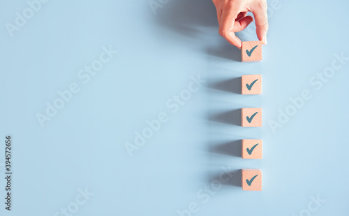 Wood cube with check mark on blue background, Checklist concept, Copy space. photo