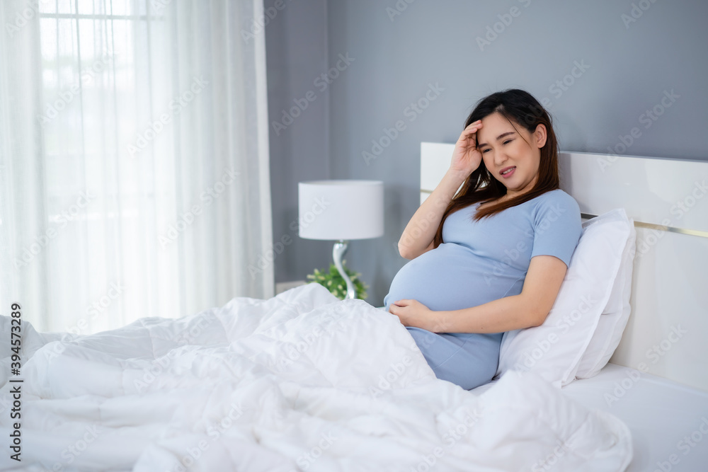 stressed pregnant woman has a headache on bed stressed pregnant woman has a headache on bed
