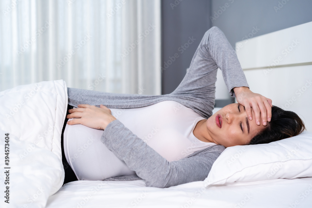 pregnant woman suffering headache lying in bed pregnant woman suffering headache lying in bed