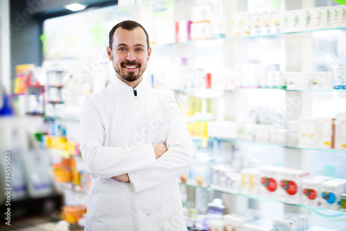 Cheerful pharmacist showing assortment of drugs in pharmacy