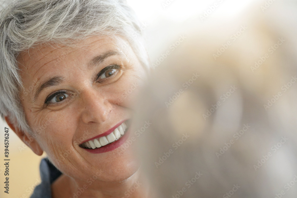Mature white-haired woman checking eye wrinkles in front of mirror Mature white-haired woman checking eye wrinkles in front of mirror