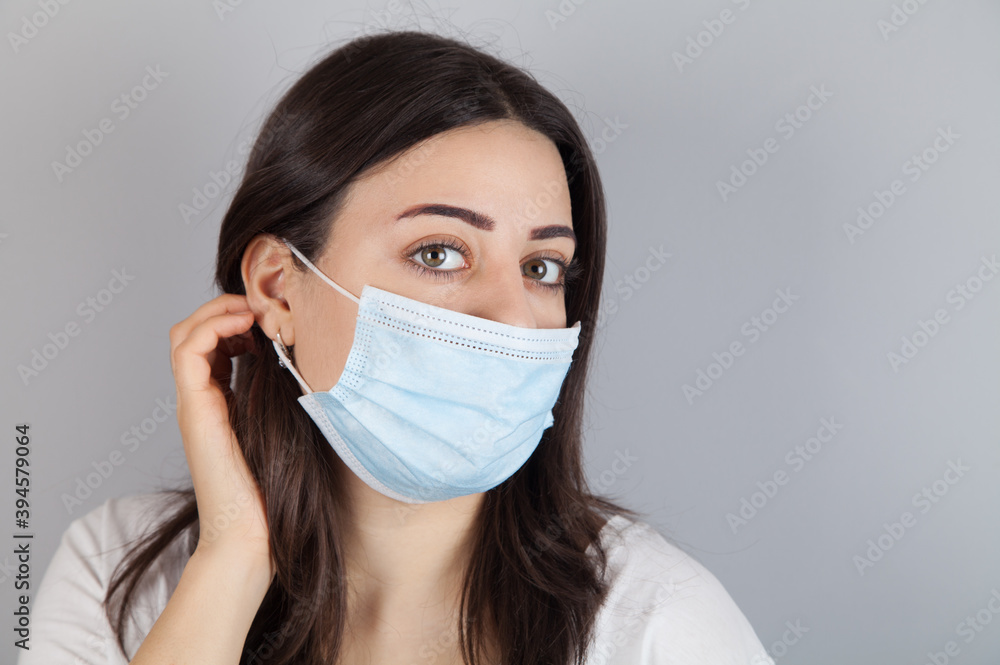 Portrait of young woman wearing medical mask at gray background. Coronavirus concept. Portrait of young woman wearing medical mask at gray background. Coronavirus concept.