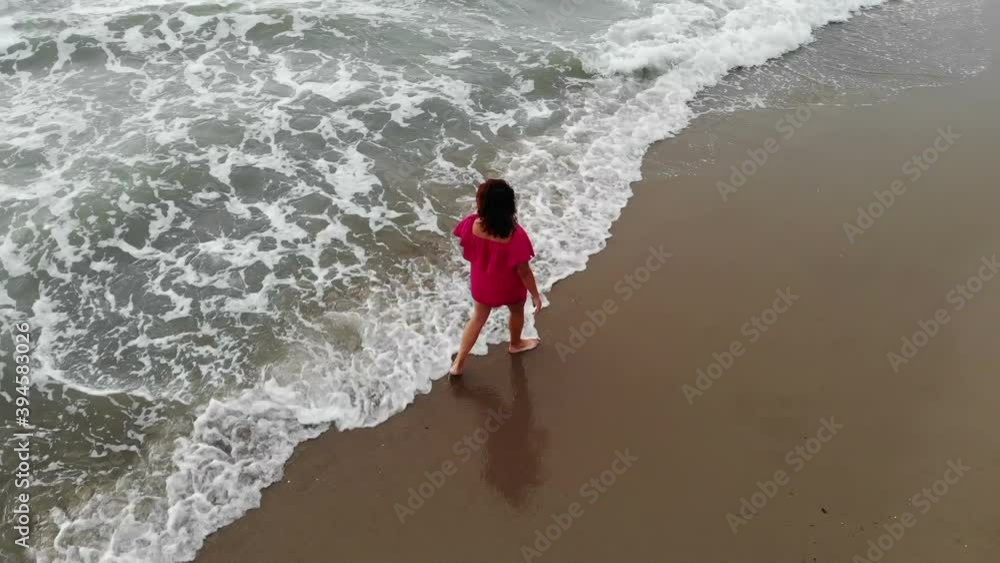woman in a dress walking into the water by sand beach on the seaside on sunset, inspirational freedom happy holidays concept, aerial shot from drone, view from above woman in a dress walking into the water by sand beach on the seaside on sunset, inspirational freedom happy holidays concept, aerial shot from drone, view from above