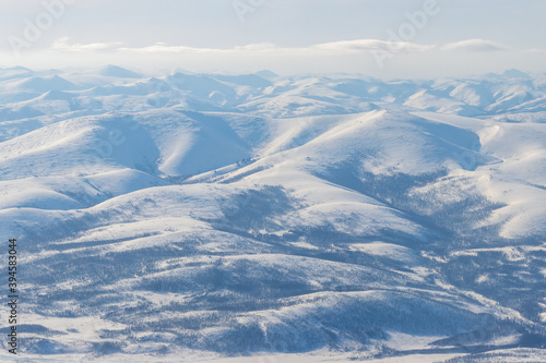 Aerial view of snow-capped mountains. Winter snowy mountain landscape. Air travel to the far North of Russia. Kolyma Mountains, Magadan Region, Siberia, Russian Far East. Great for the background.