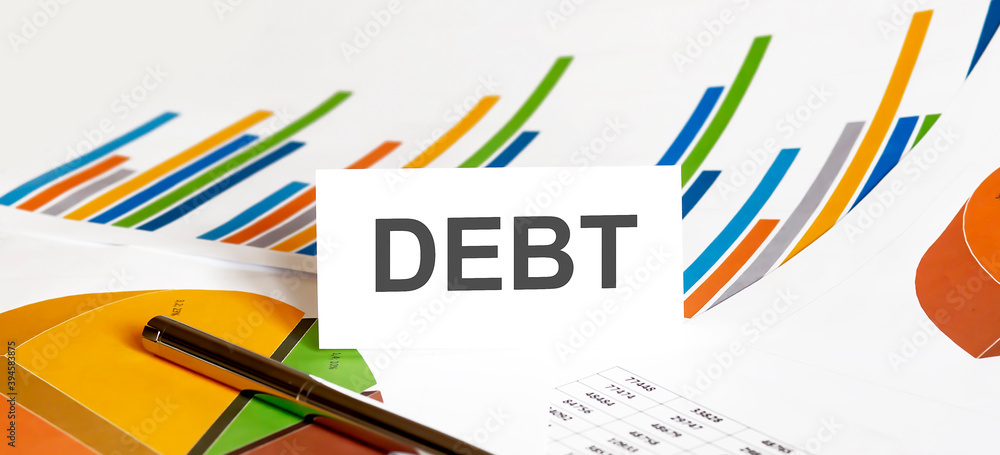 DEBT text on paper on chart background with pen DEBT text on paper on chart background with pen