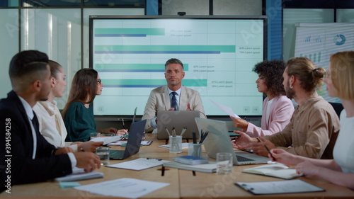 Foto Chief executive male talking with colleagues about financial success in office