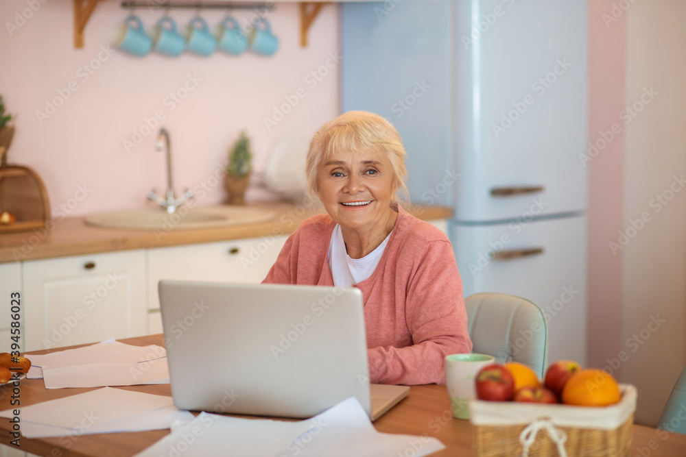 Senior woman working on a laptop and looking contented Senior woman working on a laptop and looking contented