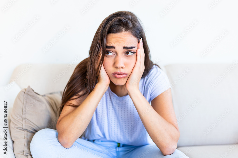 Young hopeless woman suffering from depression and anexiety. Having nervous breakdown. Sad and depressed young woman sitting on a couch in the living room at home Young hopeless woman suffering from depression and anexiety. Having nervous breakdown. Sad and depressed young woman sitting on a couch in the living room at home