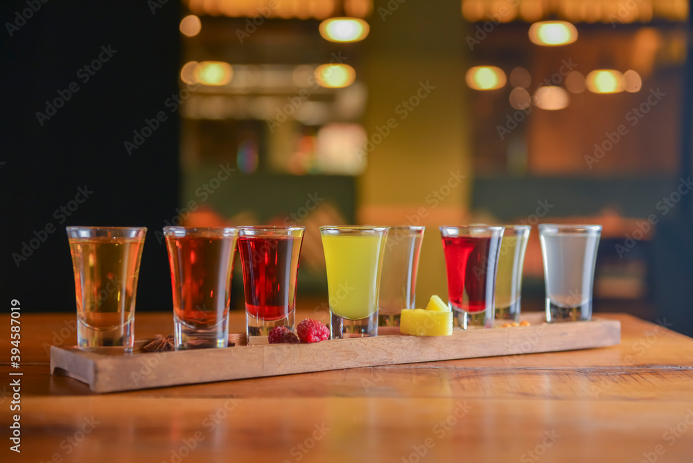 Tincture alcoholic in small shot glasses. Natural fruit alcohol drinks, shots served on a wooden table.