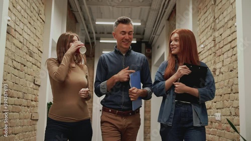 Business woman and mature man walking towards the camera in a corridor. People go to a work meeting.