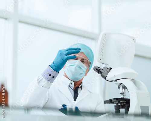 scientist in with an ampoule sitting at a laboratory table .