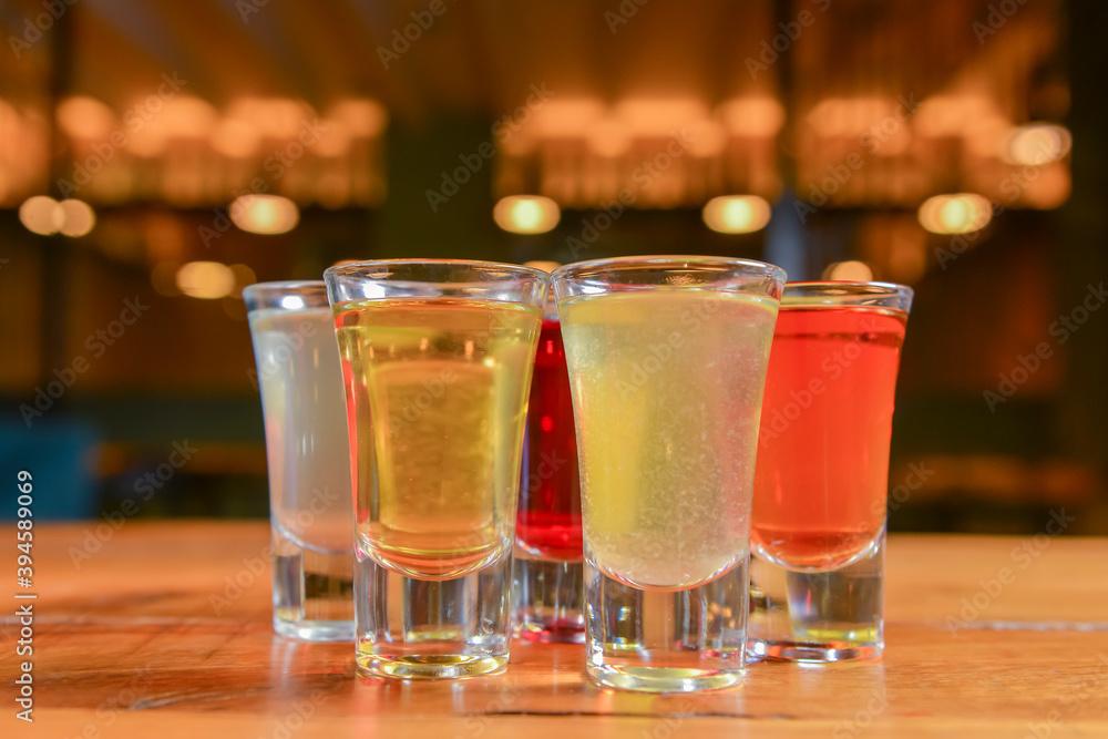 Tincture alcoholic in small shot glasses. Natural fruit alcohol drinks, shots served on a wooden table. Tincture alcoholic in small shot glasses. Natural fruit alcohol drinks, shots served on a wooden table.