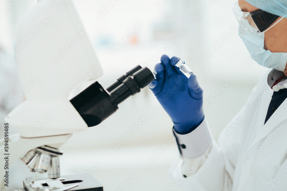 ambitious scientist looking at an ampoule with a new drug. ambitious scientist looking at an ampoule with a new drug.