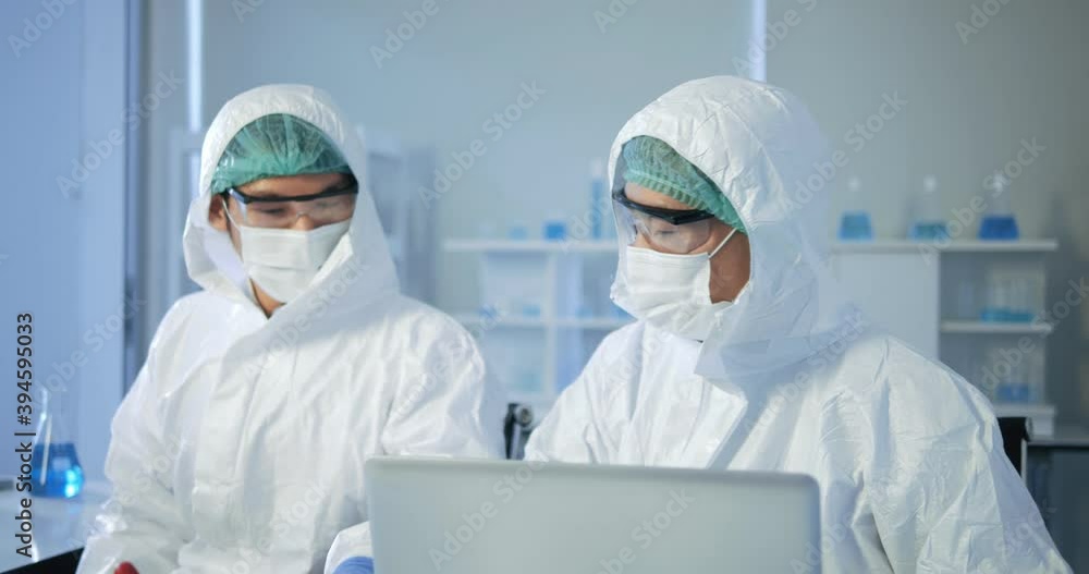 Asian man doctor scientist writing analysis results in the laboratory. Young scientist doing some research. He's Conducts Experiments in Modern Laboratory. Asian man doctor scientist writing analysis results in the laboratory. Young scientist doing some research. He's Conducts Experiments in Modern Laboratory.