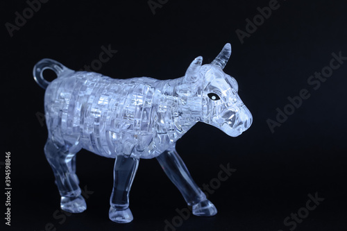 Figurine of a bull from three dimensional puzzles on black background. Symbol of coming New Year 2021, business, stock exchange, finance. 