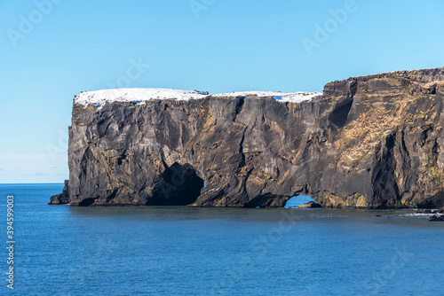Aerial winter landscape view of Dyrholaey, Iceland.  Beautiful winter view of picturesque peninsula with black sand beach, lighthouse and large arch of volcanic rocks in the ocean.