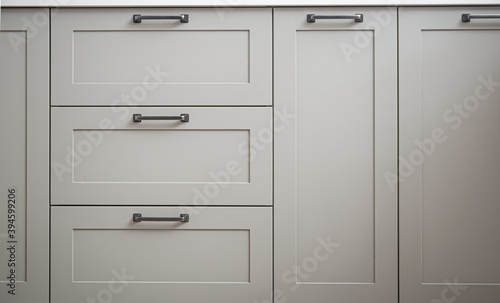 White kitchen cabinets with metal pulls or knobs on the doors. © puhimec