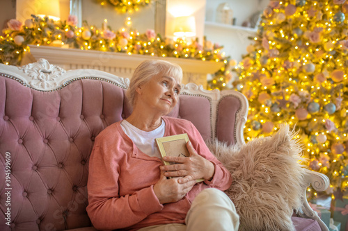 Принти на полотні Senior woman sitting on a sofa with a photo in her hand and feeling lonely