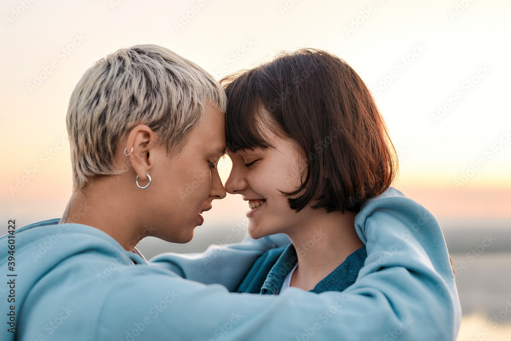 Fototapeta premium Close up of young loving lesbian couple hugging before kiss while admiring the sunrise together