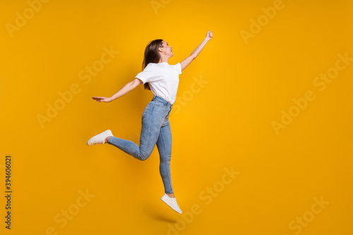 Full length body size photo of carefree girl with long hair jumping keeping hand up imagine isolated on bright yellow color background
