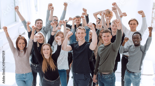 large group of happy young people with hands up