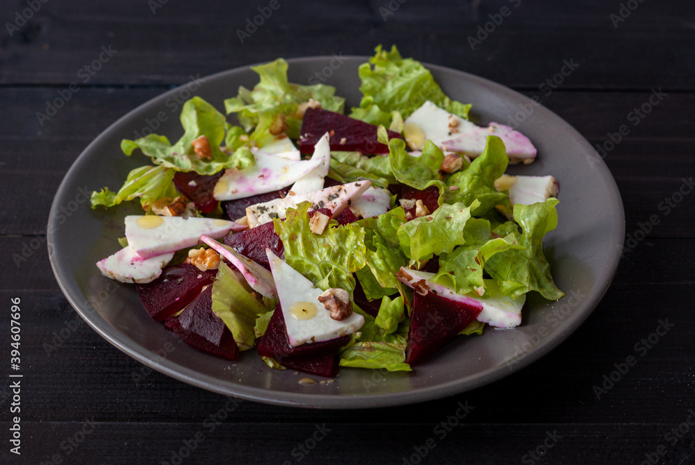 Baked beetroot salad with soft cheese and nuts in a dark plate