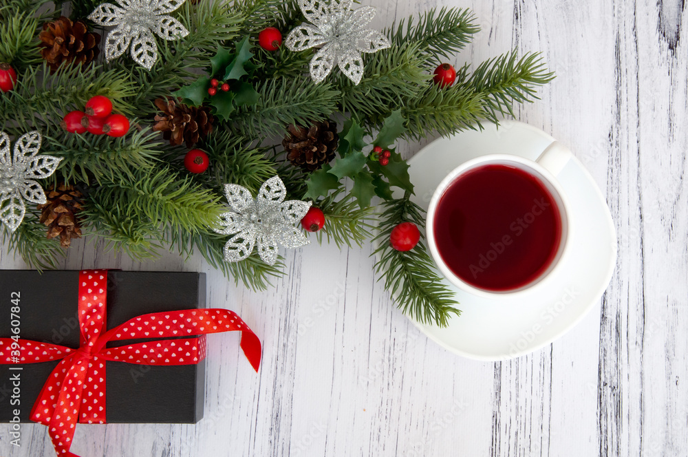 Decorated branches of a Christmas tree, cones, red berries, gifts and a cup of tea on a wooden table. Christmas decor. Decorated branches of a Christmas tree, cones, red berries, gifts and a cup of tea on a wooden table. Christmas decor.