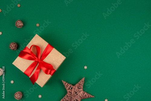 Top view of craft Merry Christmas gift with red bow ribbon and decorations over green background.