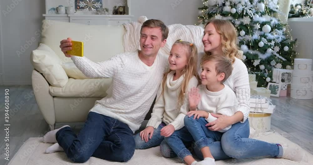 Caucasian family using smartphone celebrating Christmas with their friends using a video call. Family greeting your relatives on Christmas eve online. Social distancing, self isolation during quaranti Caucasian family using smartphone celebrating Christmas with their friends using a video call. Family greeting your relatives on Christmas eve online. Social distancing, self isolation during quaranti