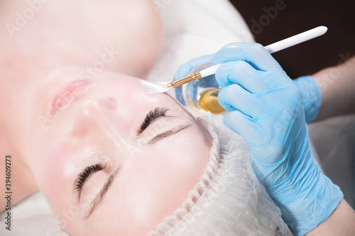 Beautician in a beauty salon puts a protective mask on the client's face. Facial skin care and beauty treatments