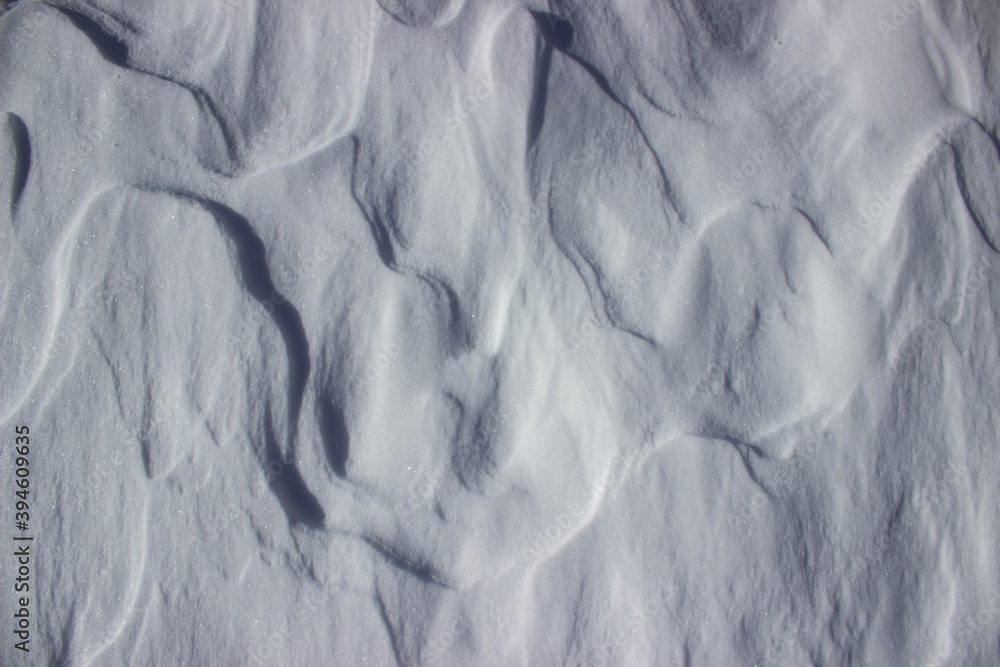 Natural white background. Snowy surface with waves formed by the wind. Abstract background. Natural white background. Snowy surface with waves formed by the wind. Abstract background.