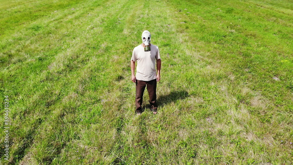 man in gas mask outdoors not able to breath, out of oxygen, in green meadow, surreal, disaster concept, arial shot from drone man in gas mask outdoors not able to breath, out of oxygen, in green meadow, surreal, disaster concept, arial shot from drone
