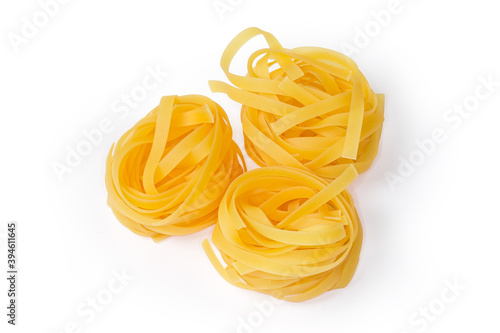 Uncooked noodle coiled into nests on a white background
