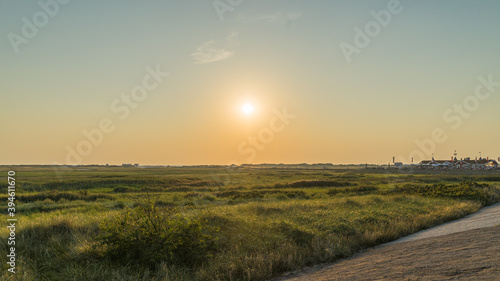 Evening view from the dike over the grassland between the dike and the beach on the North Sea coast.