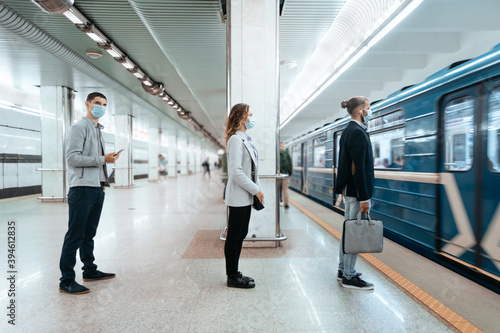 people in protective masks waiting to Board the train .