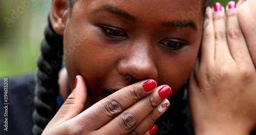 Friend reacting to shocking news, girlfriend whispering to black girl ears, sharing gossip