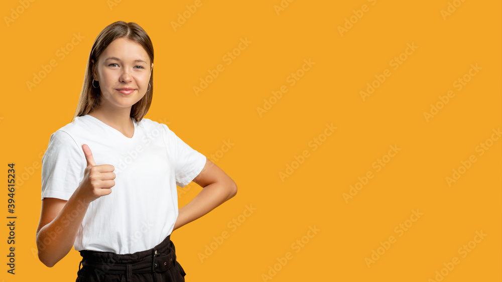 Like gesture. Advertising background. Perfect choice. approval sing. Portrait of confident cheerful teen girl in white t-shirt accepting offer showing thumb up isolated on orange copy space. Like gesture. Advertising background. Perfect choice. approval sing. Portrait of confident cheerful teen girl in white t-shirt accepting offer showing thumb up isolated on orange copy space.
