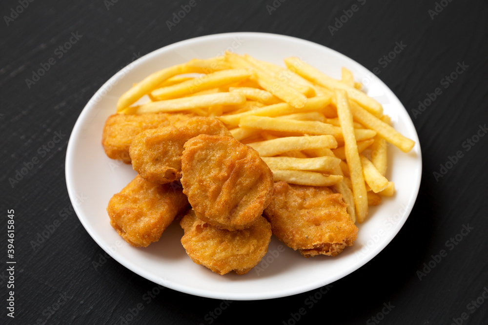 Tasty Fastfood: Chicken Nuggets and French Fries on a plate on a black background, side view. Tasty Fastfood: Chicken Nuggets and French Fries on a plate on a black background, side view.