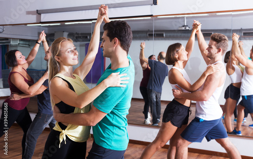 Group of young glad people learning salsa at dance class. Focus on brunet man © JackF