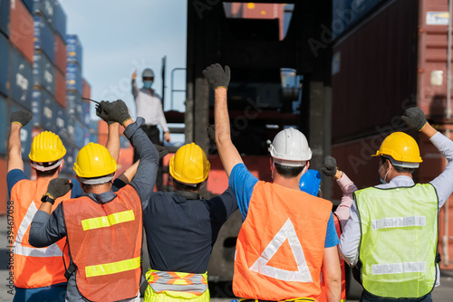 Group of people worker protesting in factory . Male group of protestors fists raised up in the air. Logistics and transportation business Containers import export concept .