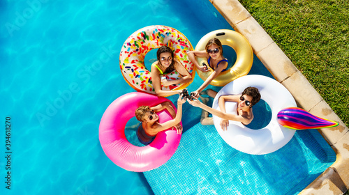 Canvas Print Group of children drink soda swimming in pool in inflatable toy doughnuts from t