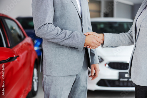 Cutout picture of car seller shaking hands with buyer while standing in car salon. © dusanpetkovic1